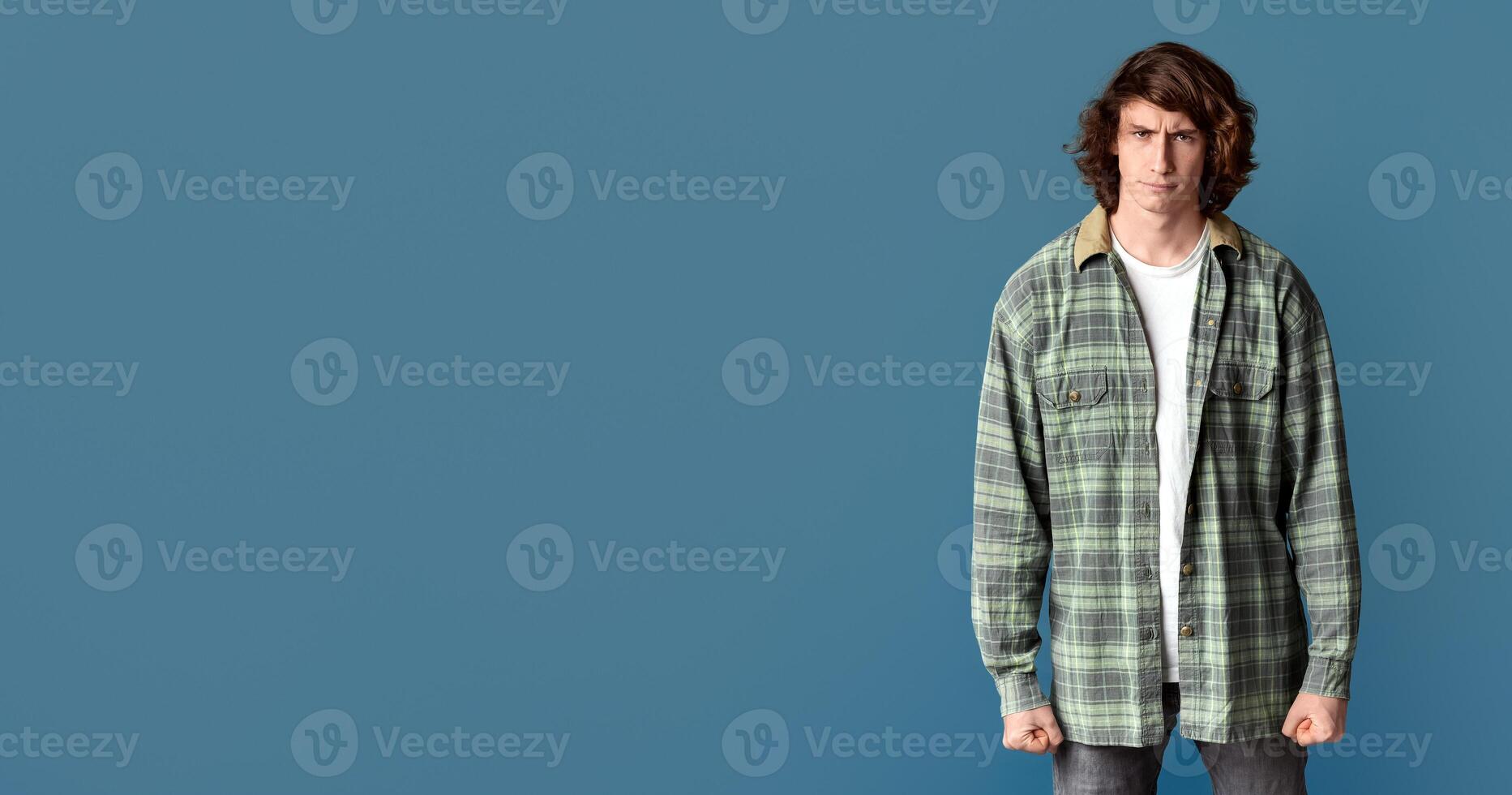 Millennial guy clenching his fists in anger and frowning on turquoise background photo