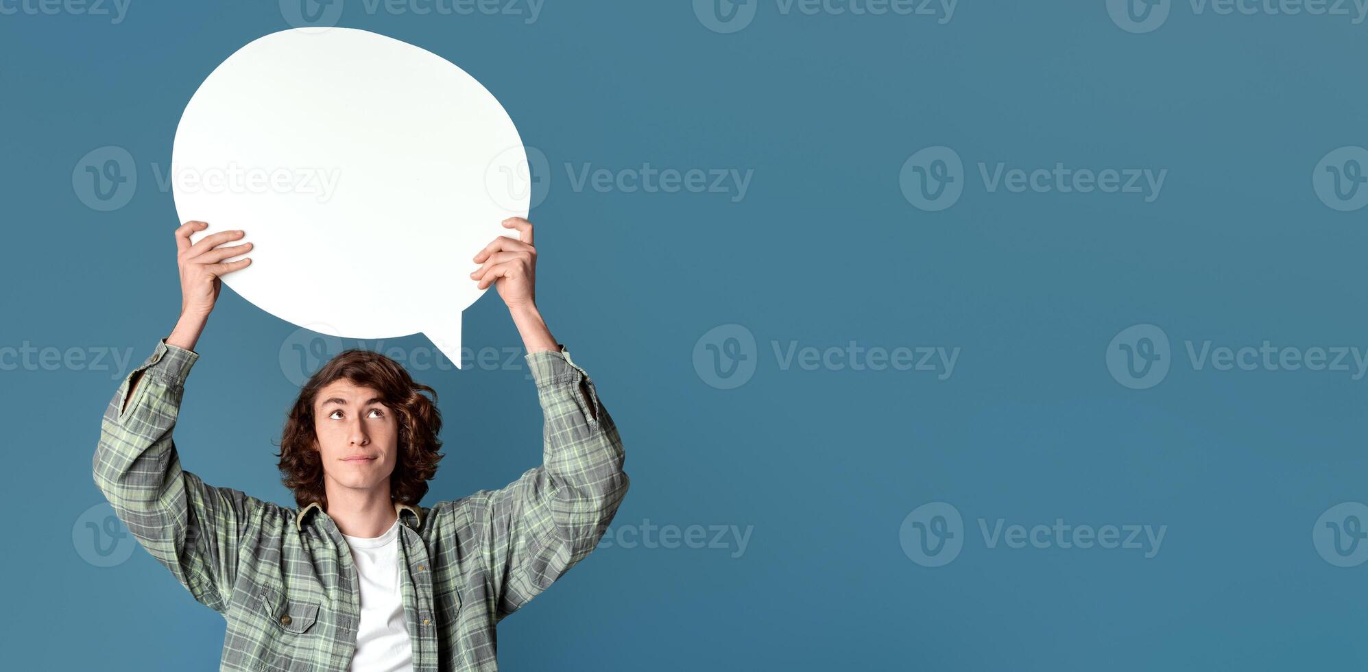 Attractive teenage guy holding speech bubble with empty space for your design, turquoise background photo