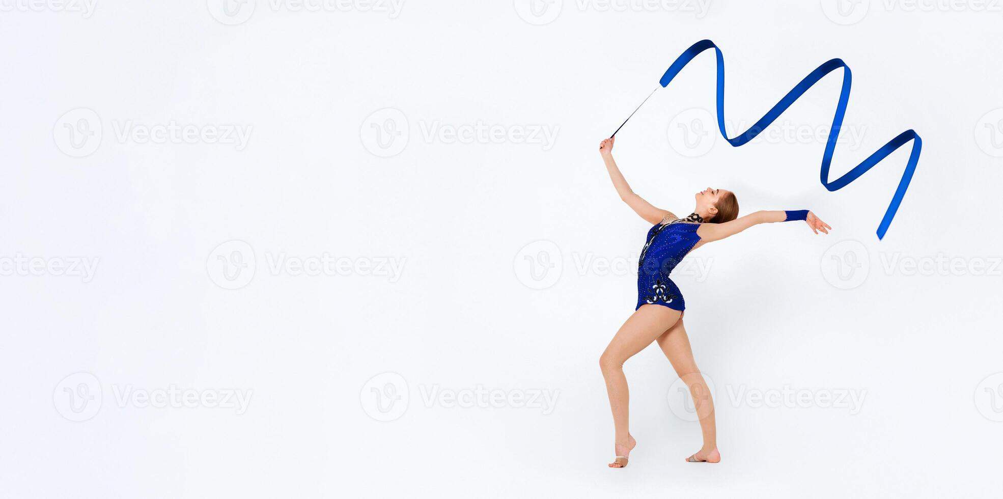 Beautiful performance. Full length portrait of charming gymnast dancing with ribbon on white background photo