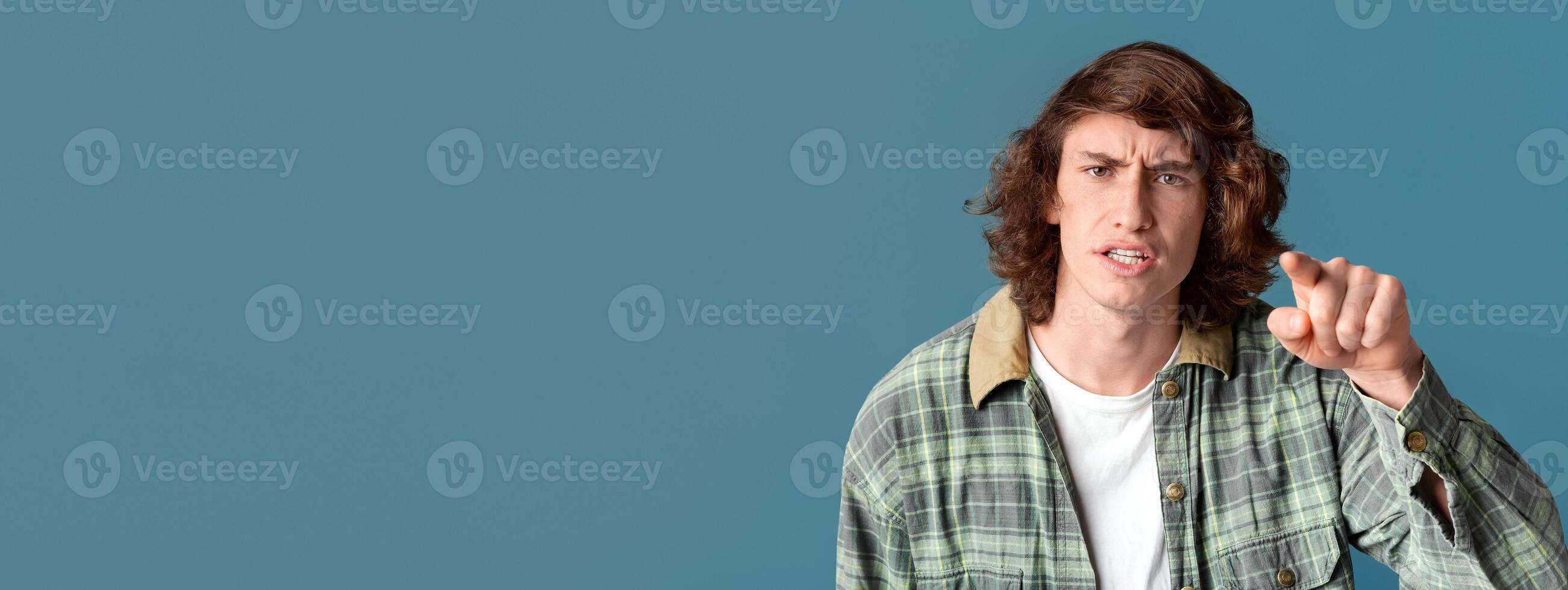 Frustrated teenager pointing finger at you in accusation on turquoise background photo