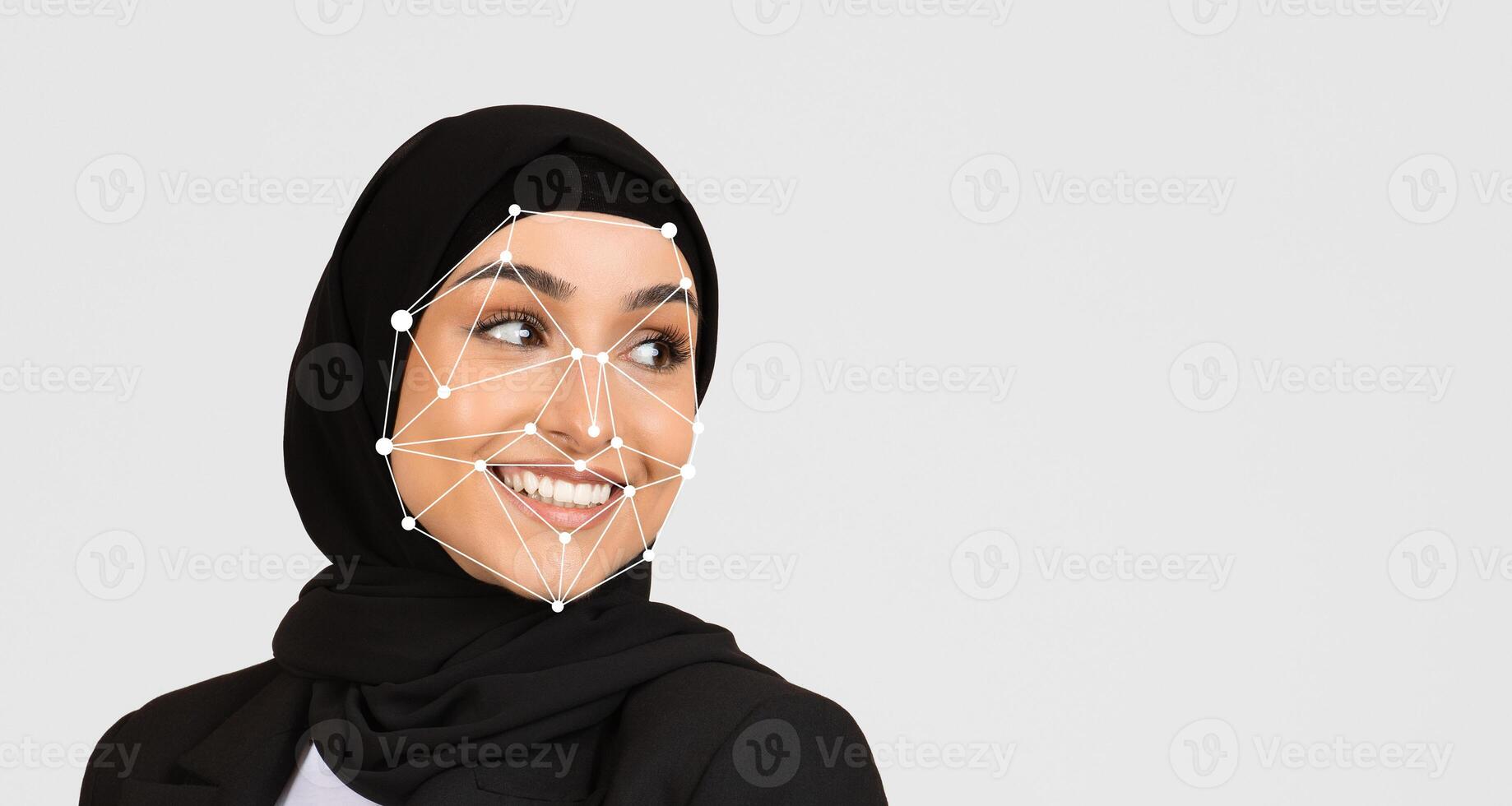 A smiling woman wearing a black hijab is captured with facial recognition technology used to map her features, showcasing a blend of technology and cultural representation. photo