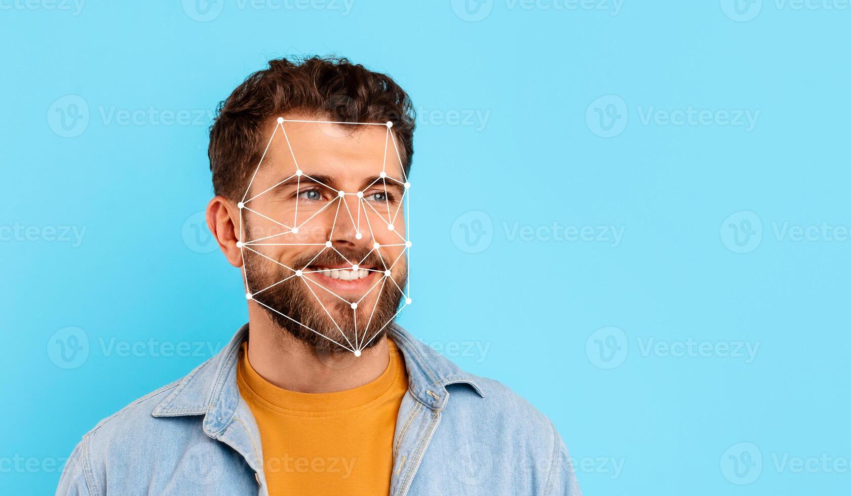 A man with a beard smiles while facial recognition technology is displayed over his face against a bright blue backdrop, showcasing modern biometric innovations. photo