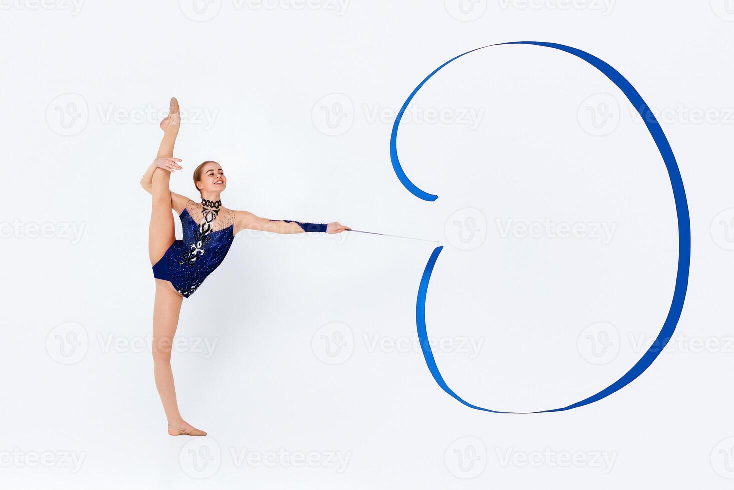 Gymnastic moves. Slender young woman in leotard doing exercises with ribbon on white background, copy space photo
