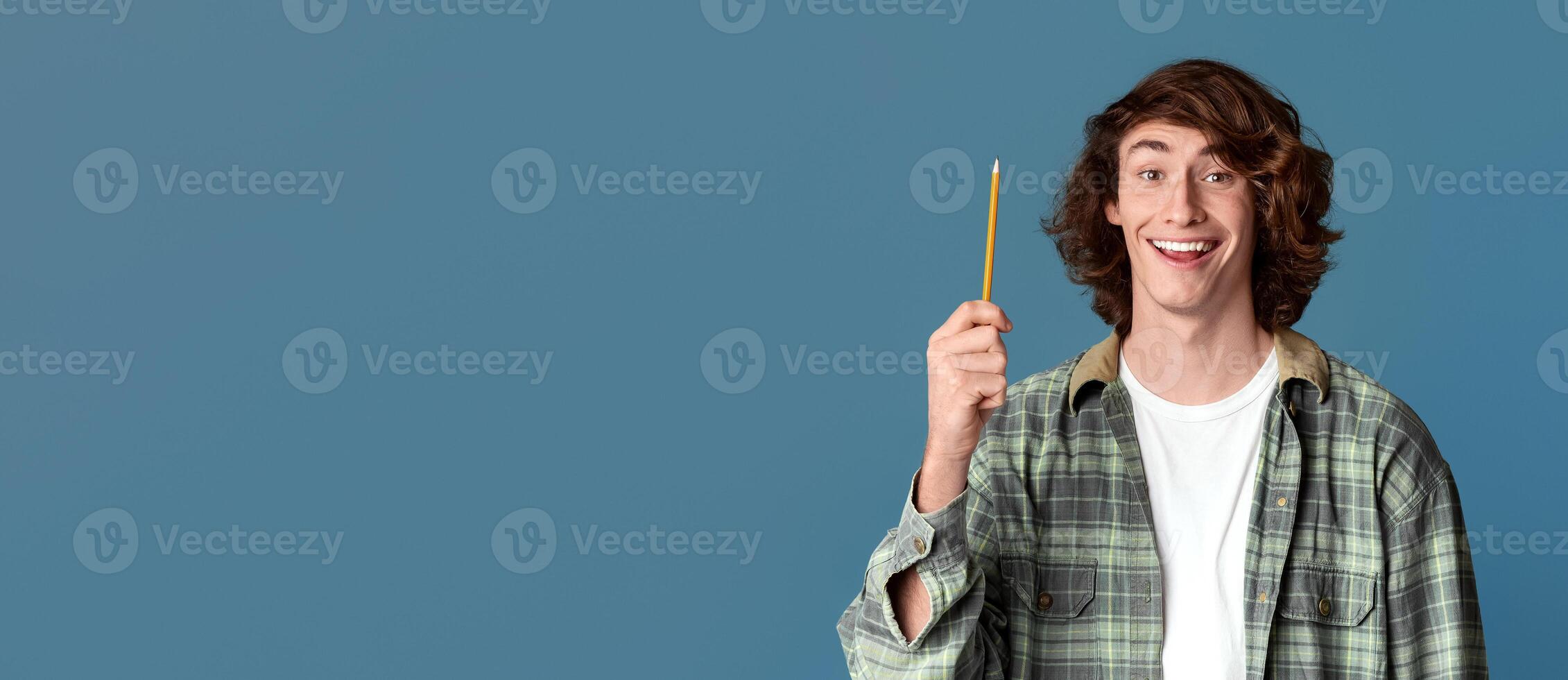 Having idea concept. Young guy pointing up pencil on color background photo