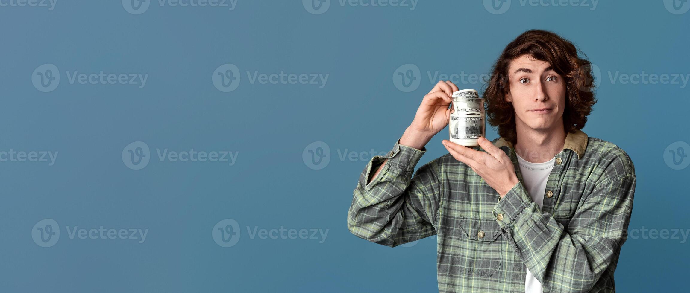Big luck concept. Rich young guy holding dollars on turquoise background photo