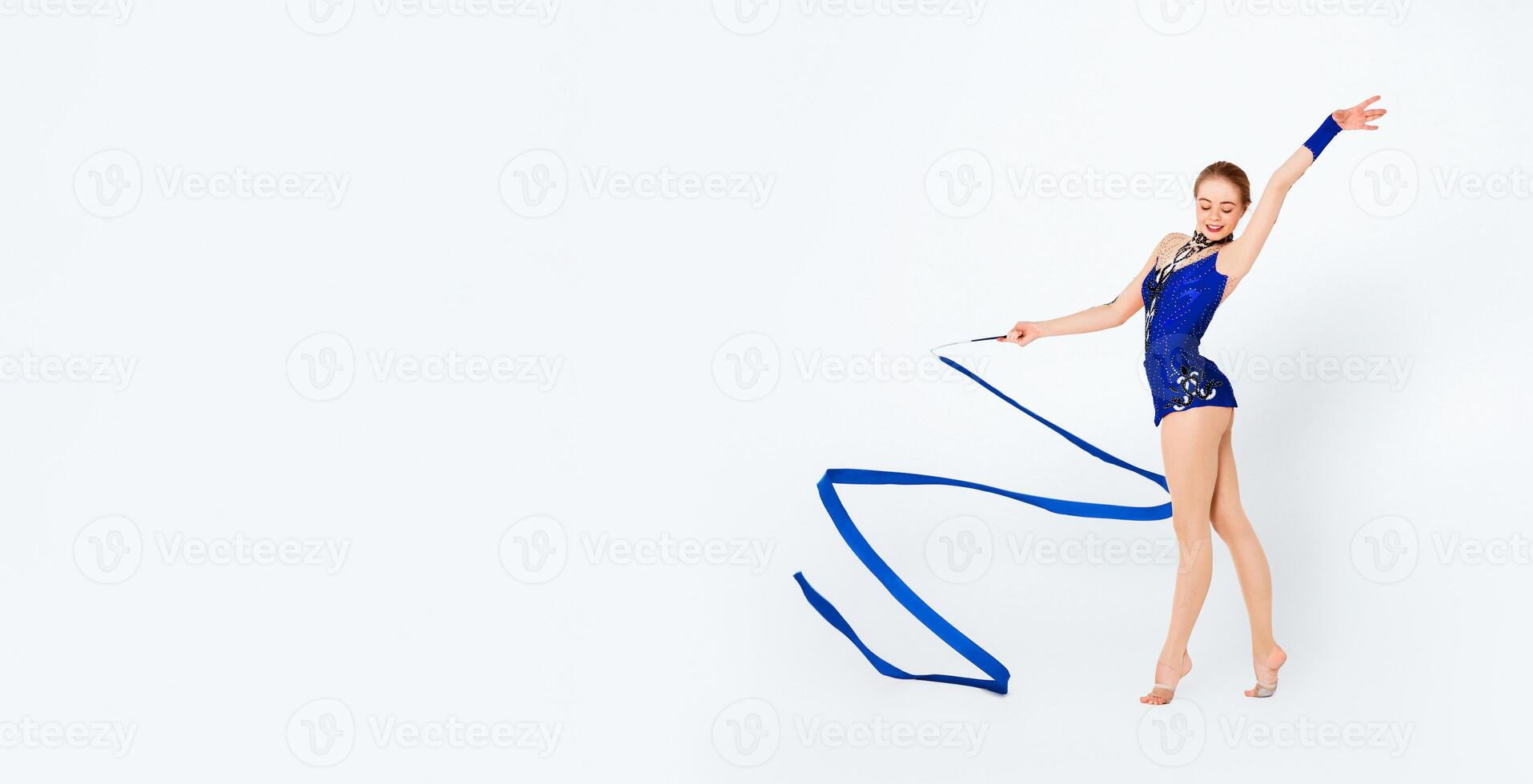 Smiling young sportswoman with gymnastic ribbon practicing on white background photo