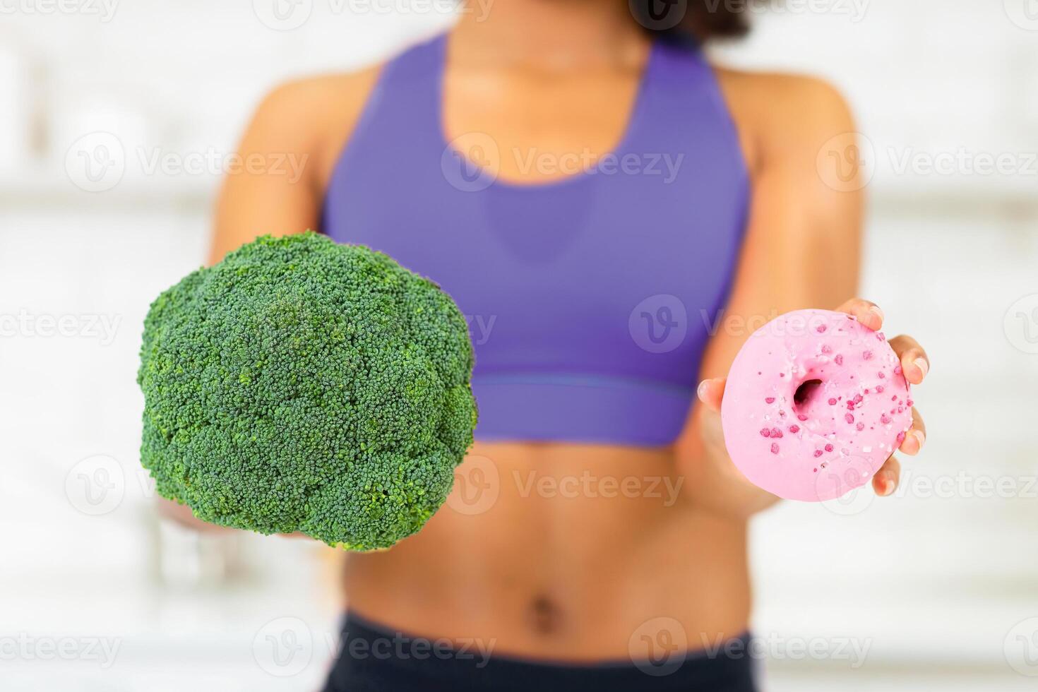Healthy Lifestyle Concept. Unrecognizable Woman Holding Broccoli And Junk Food Donut In Hands, Selective Focus photo