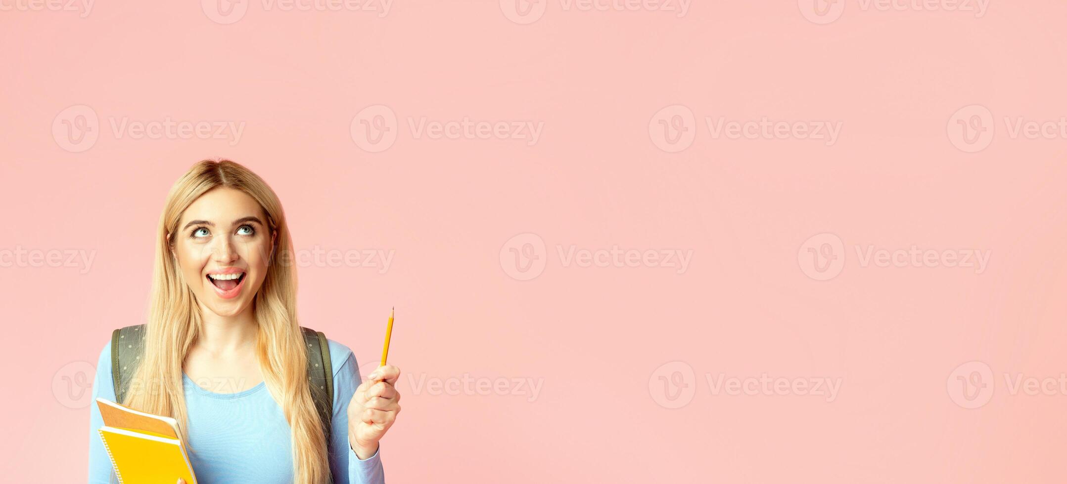 Perfect Idea. Close up portrait of teenager with opened mouth holding notebook, pointing up with pen at copyspace photo
