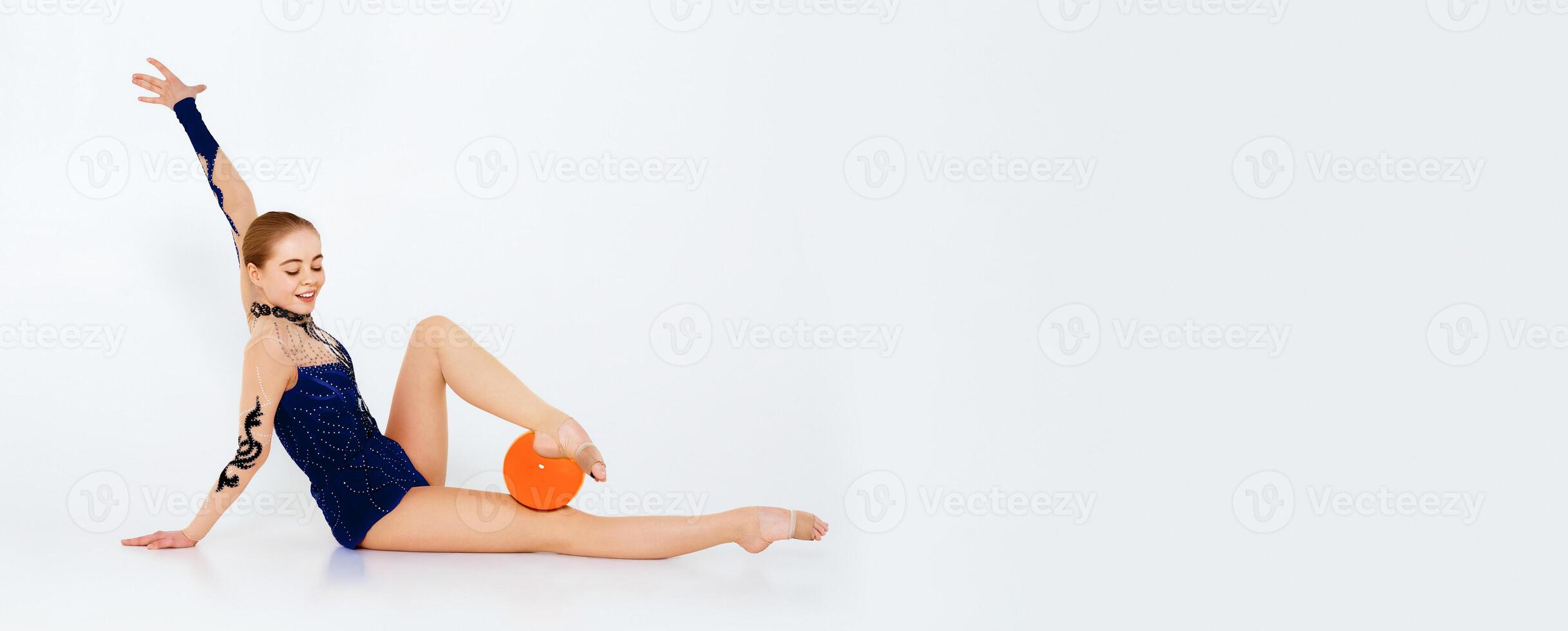 Charming girl in red gymnastic suit with ball sitting on white background photo