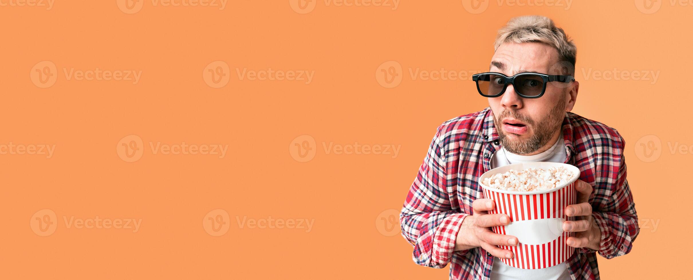 Disgust and shock from film. Surprised guy funny holding bucket of popcorn, close up photo