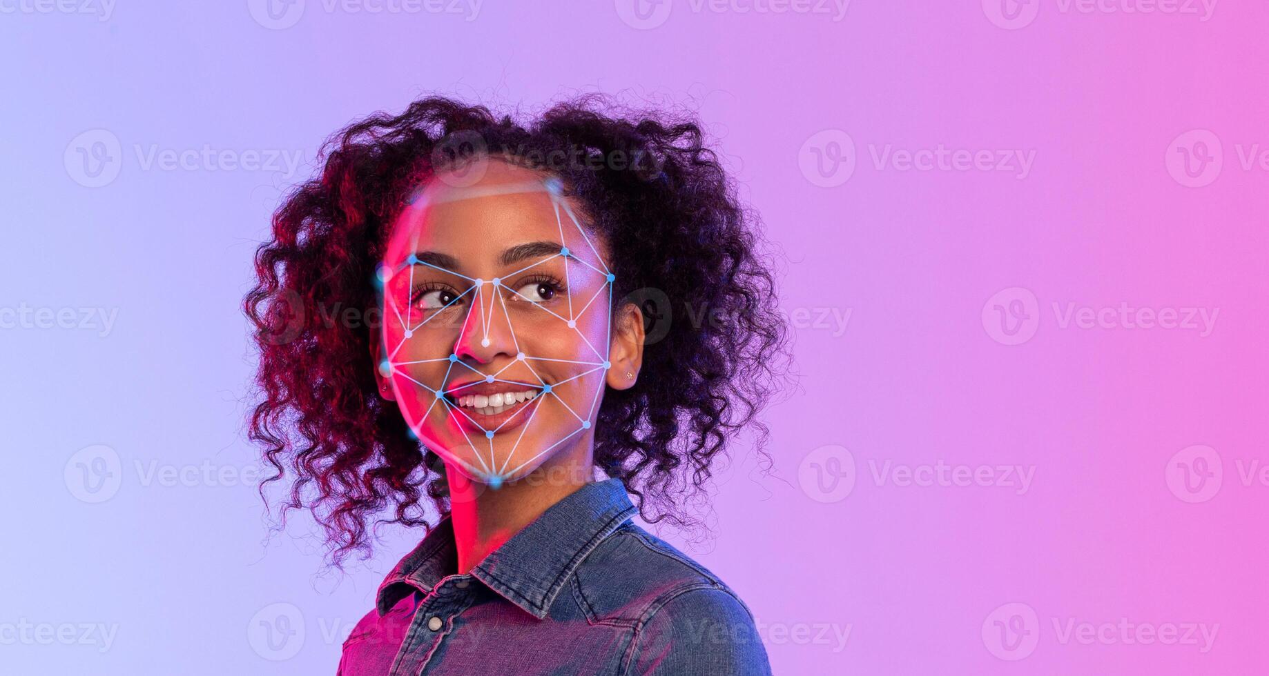 African American young woman with curly hair smiles confidently as she participates in facial recognition technology testing in a modern indoor setting illuminated with colorful lights. photo