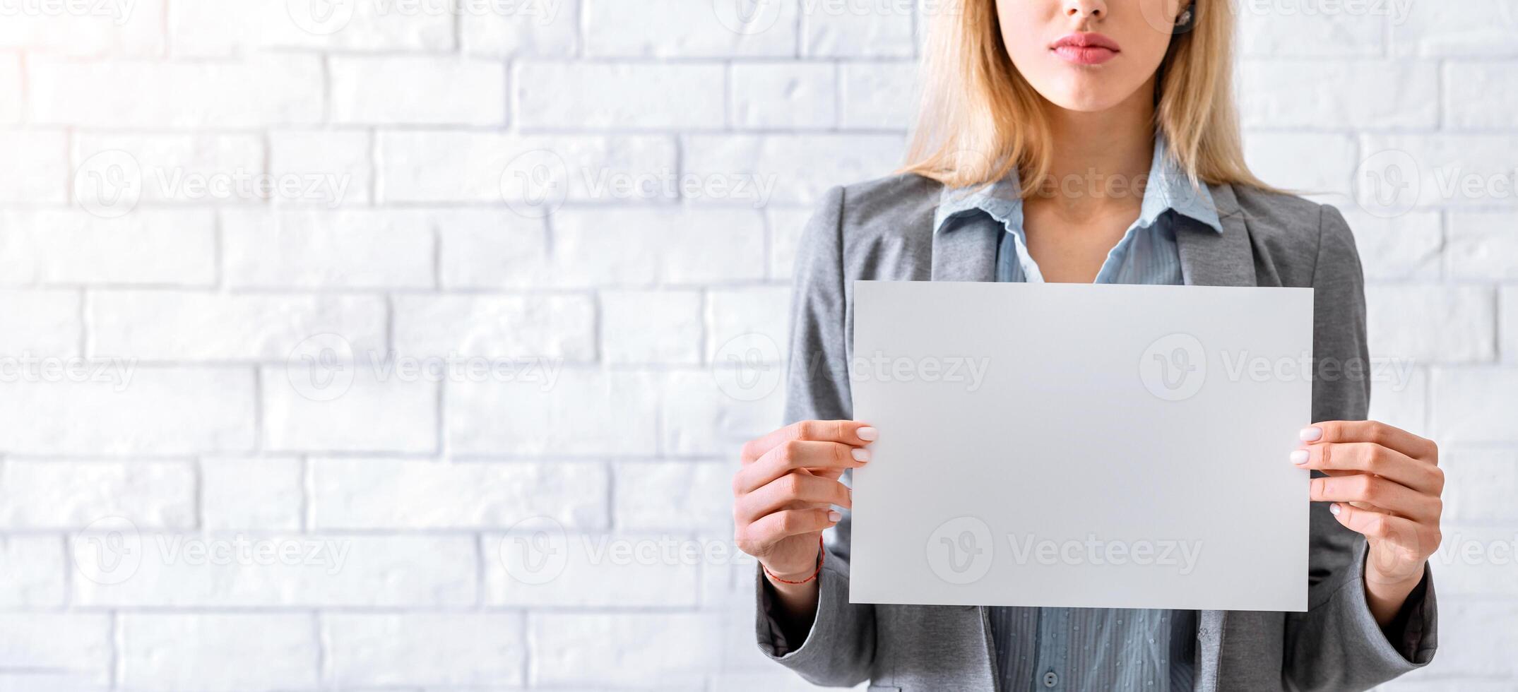Cropped woman in business suit holds empty blank paper photo