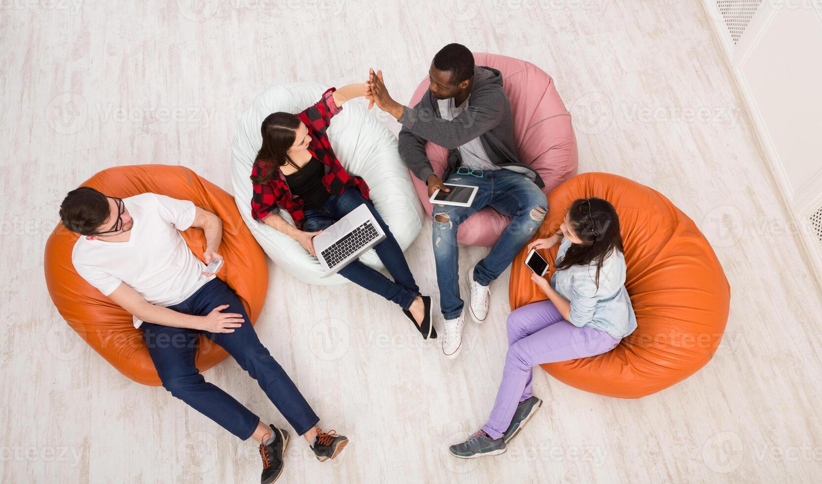 Education and technology. Young students of different nationalities using gadgets while waiting for exam at university, top view photo