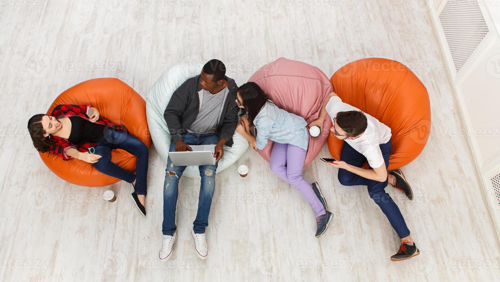 Coffee break. Group of multiethnic young students preparing for exams in home interior, using gadgets photo