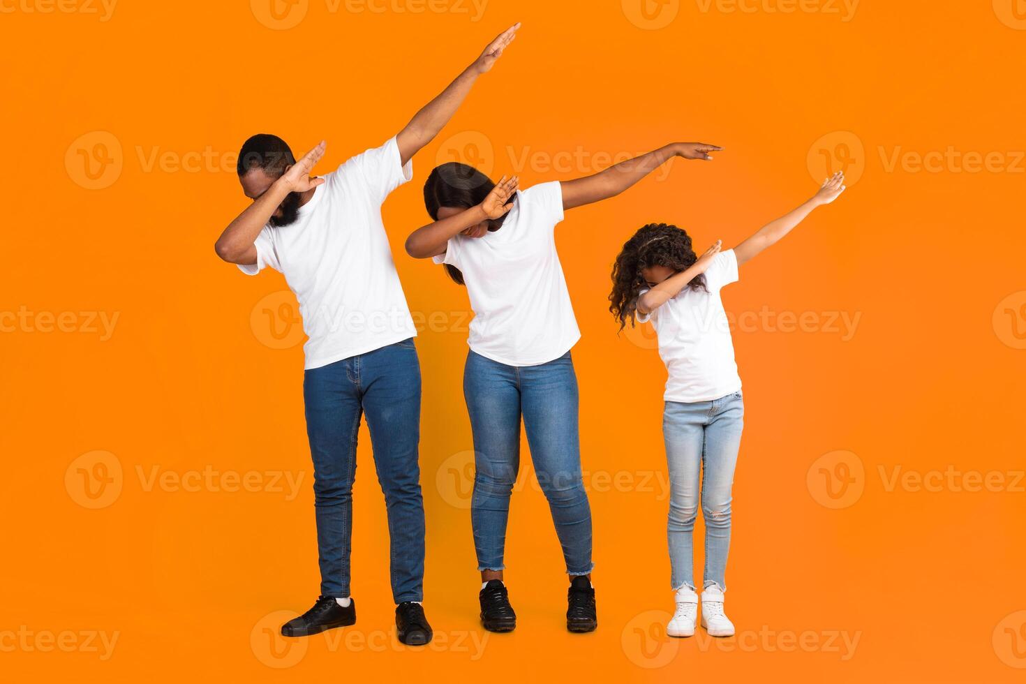 Black Family Of Three Throwing Dab Gesture Having Fun Posing Standing On Yellow Studio Background. African American Father, Mother And Daughter Making Internet Meme Dabbing Pose, Full Body Length photo