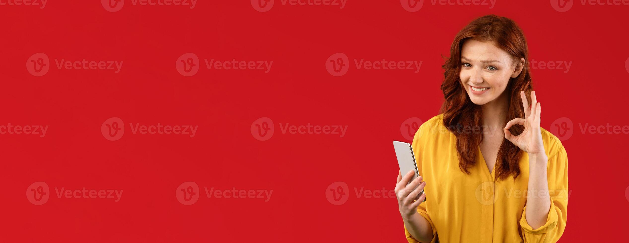 Teen Girl Using Phone Gesturing OK Recommending Mobile App Over Green Studio Background. Panorama, Empty Space photo