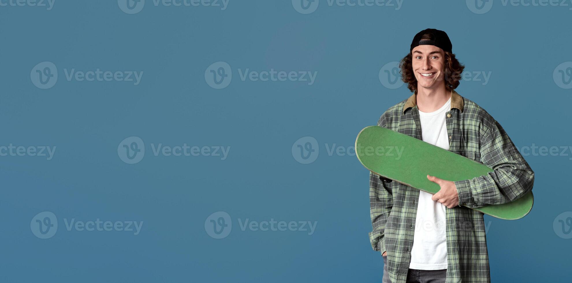Sports and leisure concept. Happy teenager with skateboard on turquoise background photo