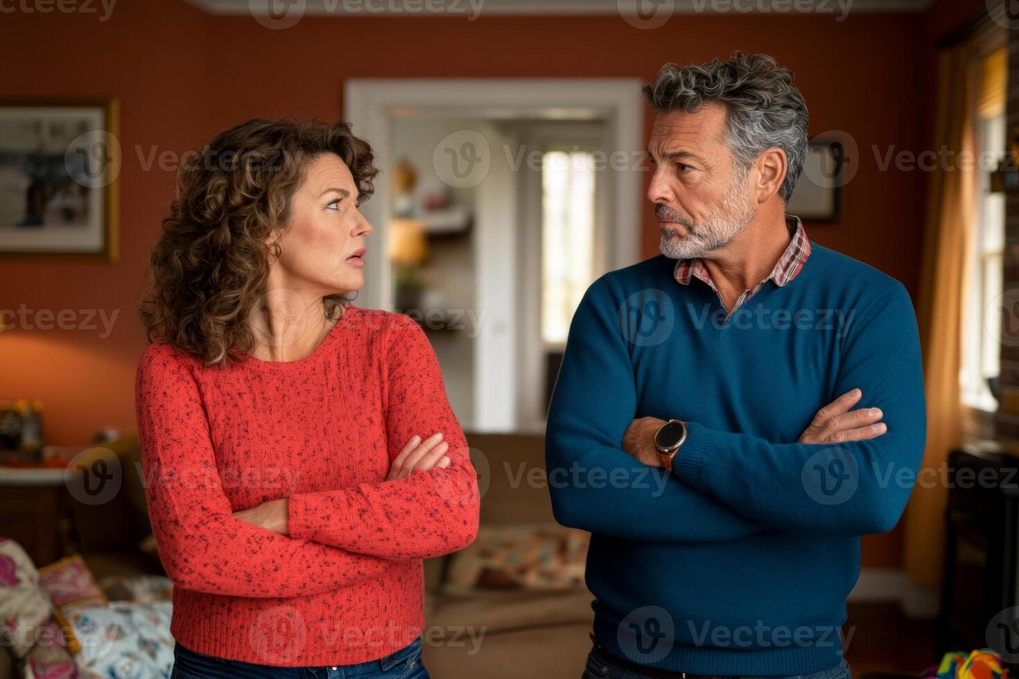A tense moment between a husband and wife in their living room, both with arms crossed, displaying angry expressions photo
