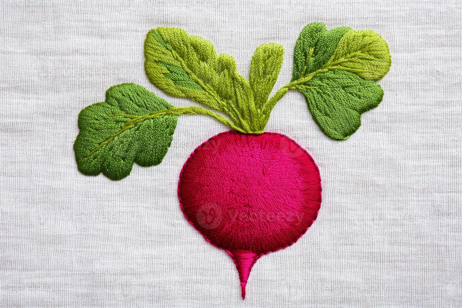An embroidered red radish with green leaves on a white fabric background photo