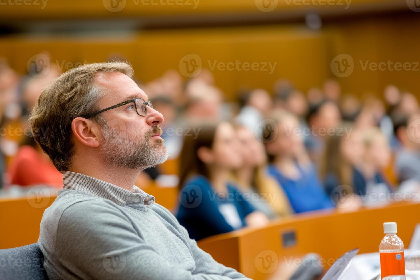 A focused attendee listening intently during a lecture in a large auditorium photo