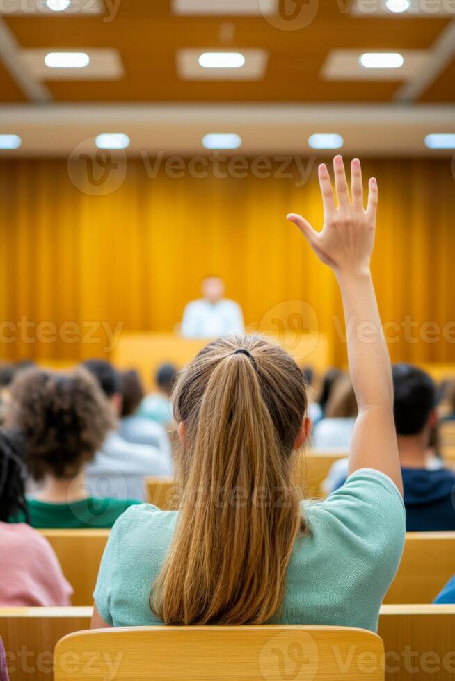 A student raising their hand during a lecture in a university classroom. photo