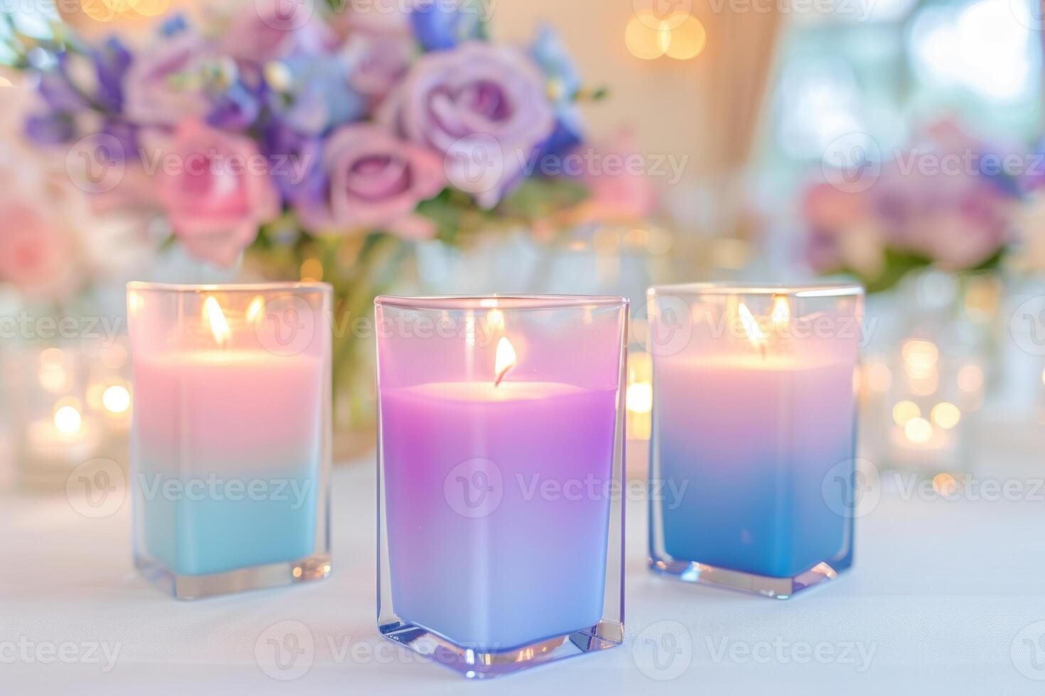 Vibrant square candles with pink-to-blue gradients glowing on a wedding reception table, surrounded by pastel floral photo