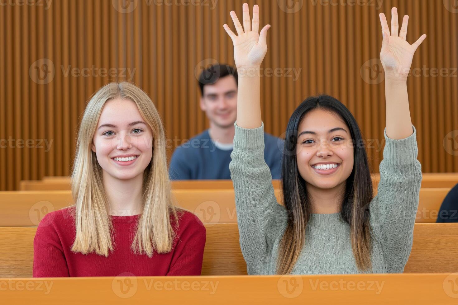 Two enthusiastic female students participating in a lecture hall discussion with a professor present photo