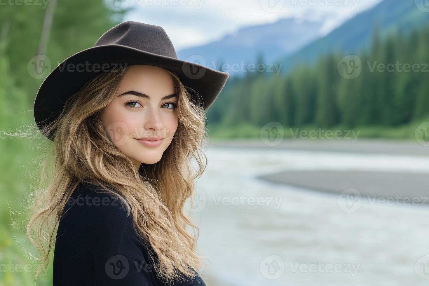 A cowgirl with windswept hair gazes thoughtfully over her shoulder by a river in a serene forest landscape photo