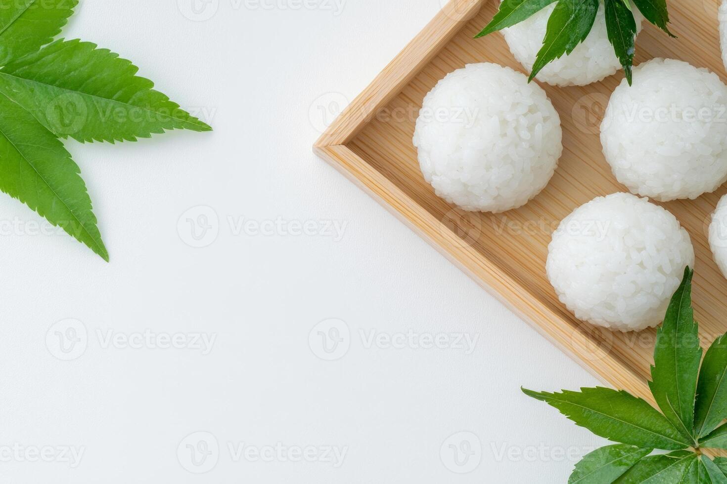Minimalist display of rice balls garnished with fresh shiso leaves on a wooden tray against a clean white background photo