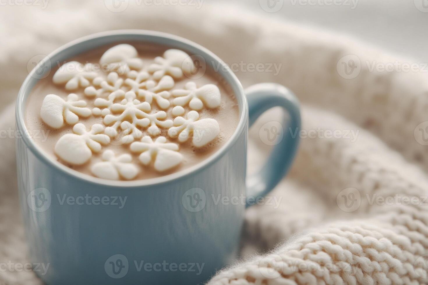 Cozy hot chocolate topped with snowflake marshmallows on a soft knit blanket for winter warmth photo