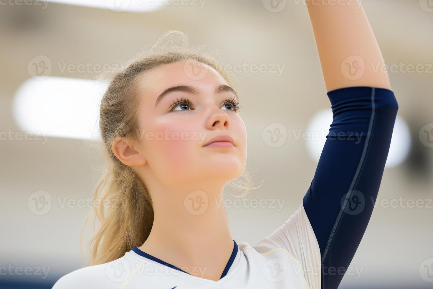 Focused young volleyball player preparing for a serve in a gym during a sunny afternoon photo