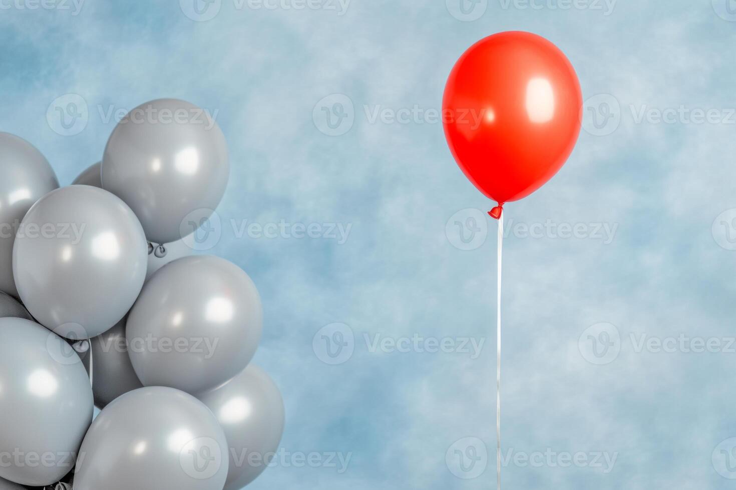 Bright red balloon stands out among gray balloons symbolizing uniqueness and individuality in a minimalistic setting photo