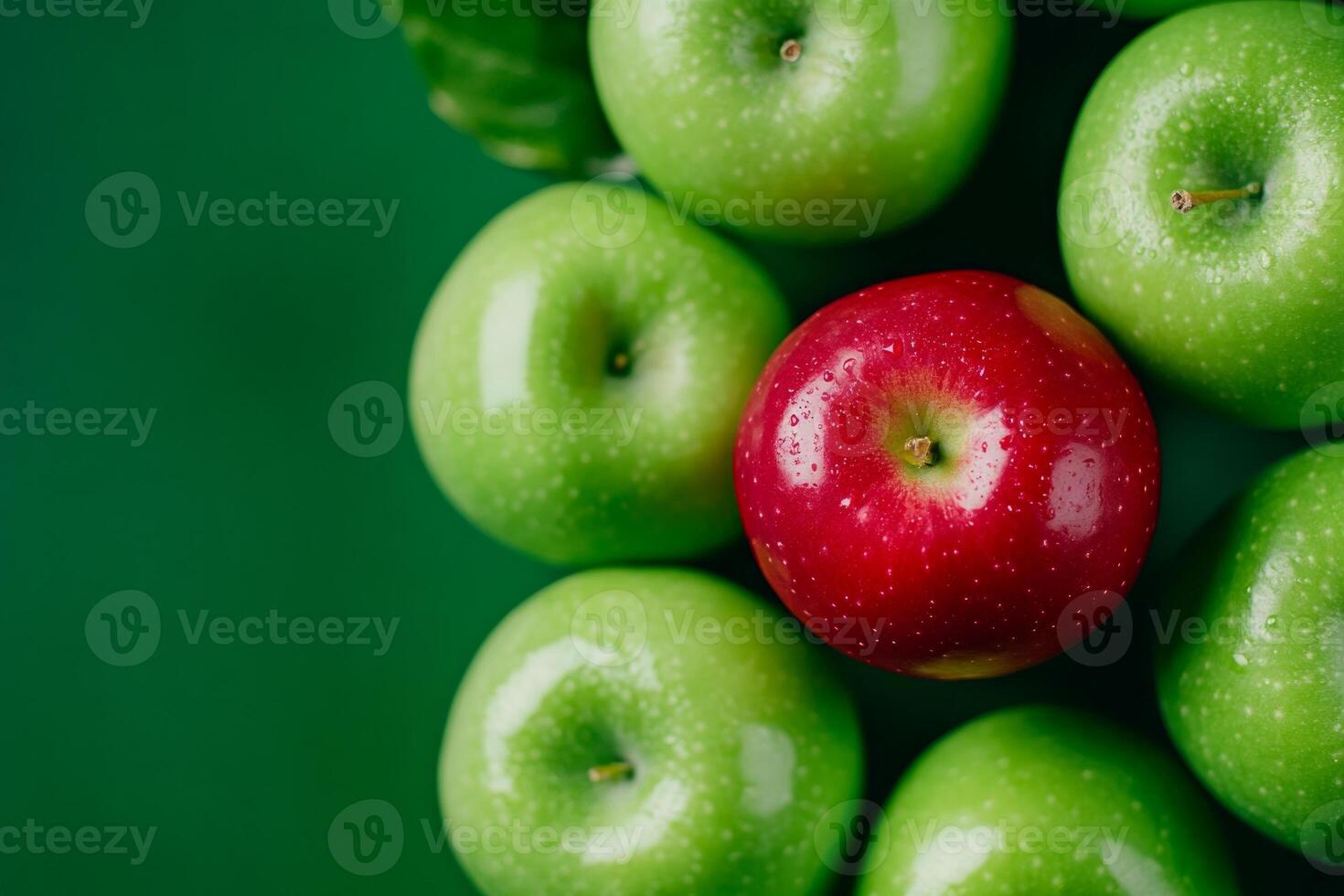 A single red apple stands out among green apples on a minimalistic background representing uniqueness and diversity photo