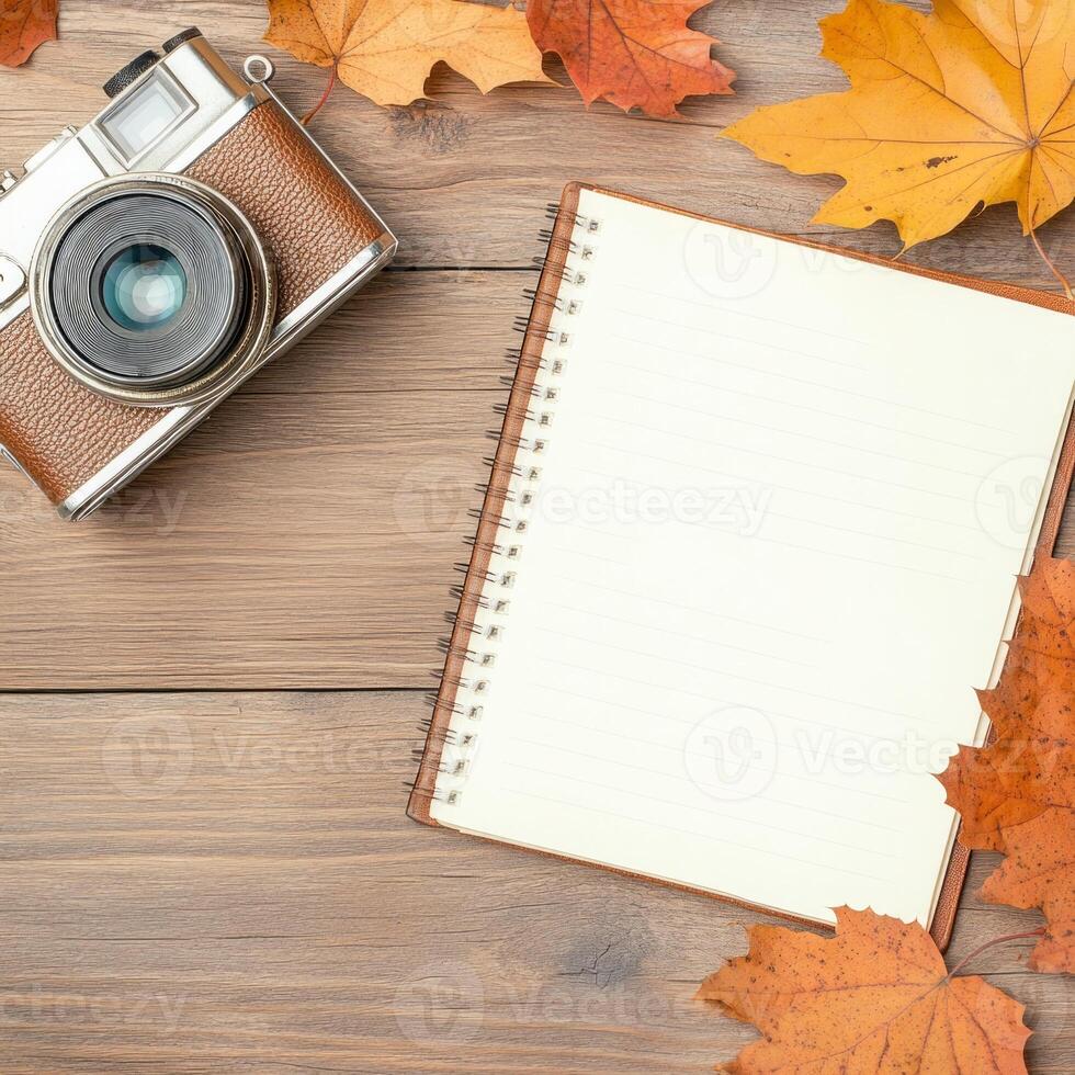 Vintage camera with travel notebook and autumn leaves on wooden table photo
