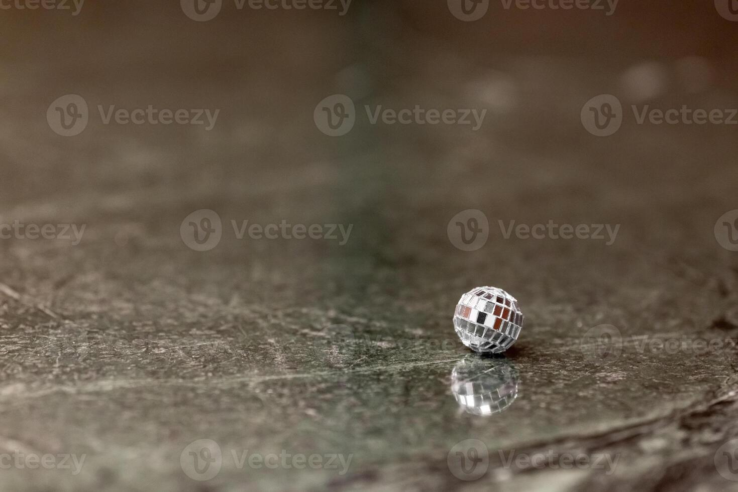 A small disco ball on a stone table. Club concept. New Year decoration photo