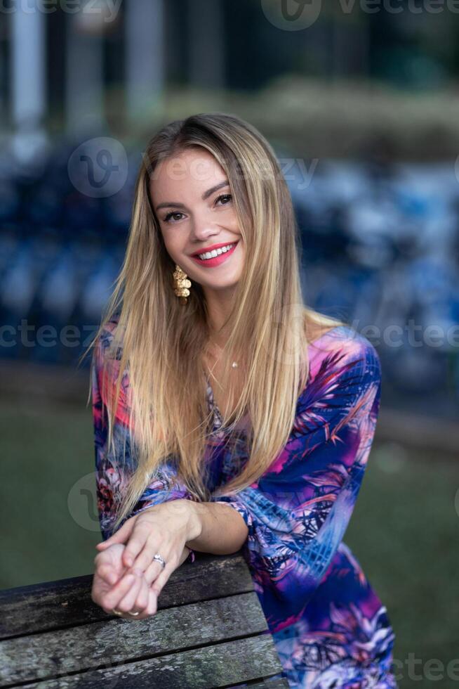 Beautiful blond young woman in long colorful dress photo
