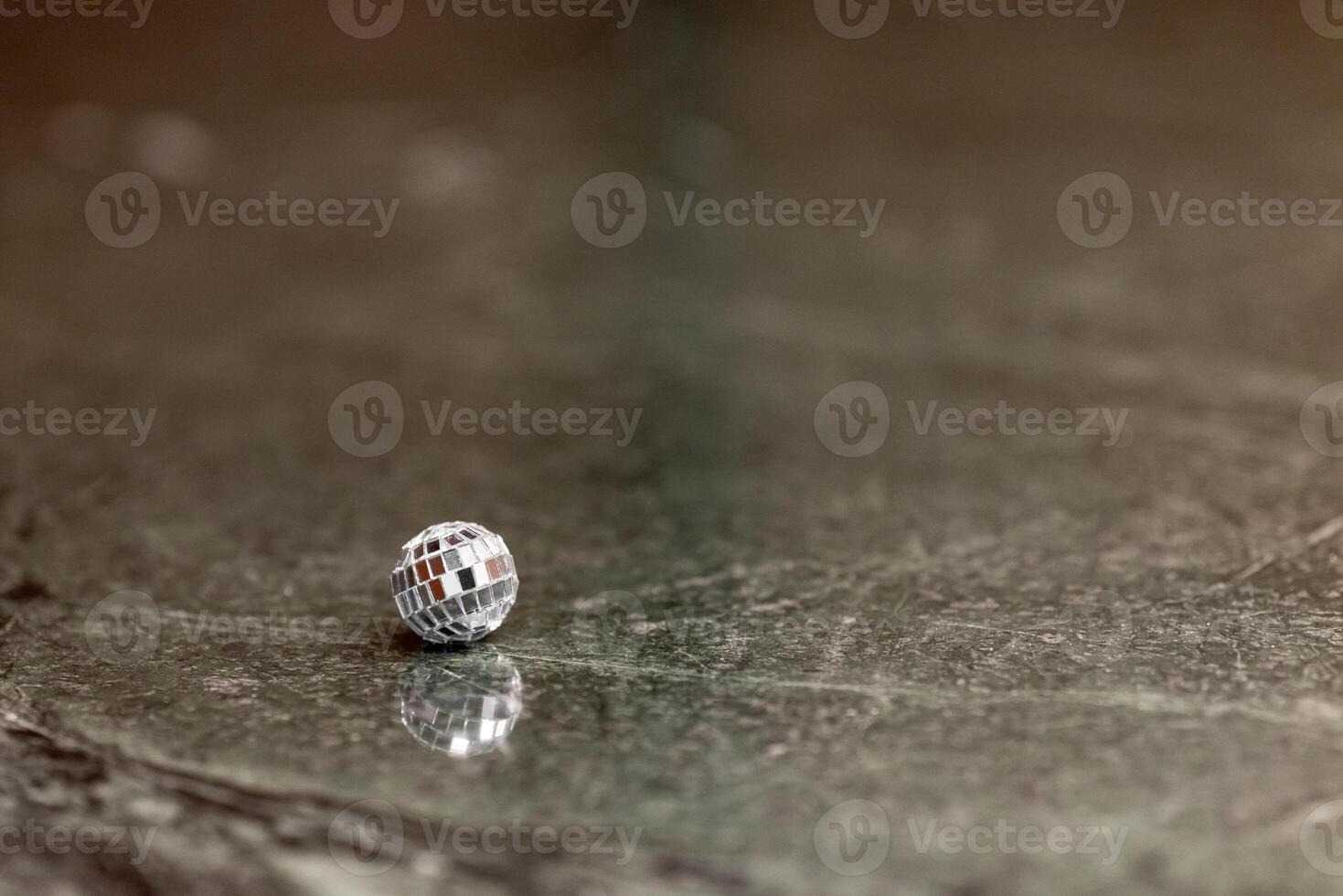 A small disco ball on a stone table. Club concept. New Year decoration photo