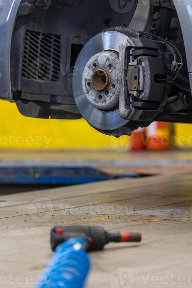 Car mechanic working in garage and changing wheel alloy tires, repair and maintenance auto service, vehicle service concept photo