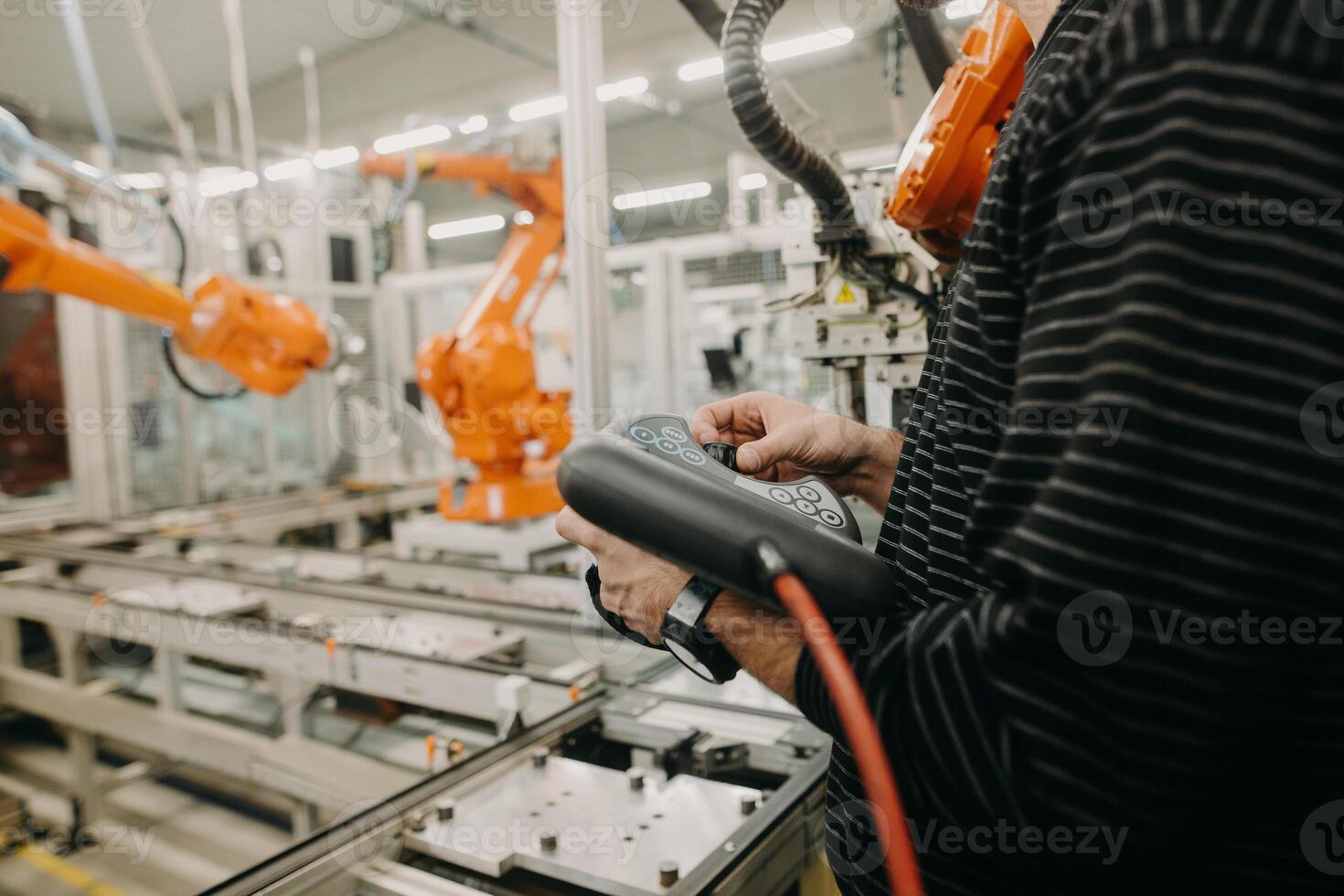 Technical engineer adjusting a robotic arm in the industrial automotive hall, industry concept photo
