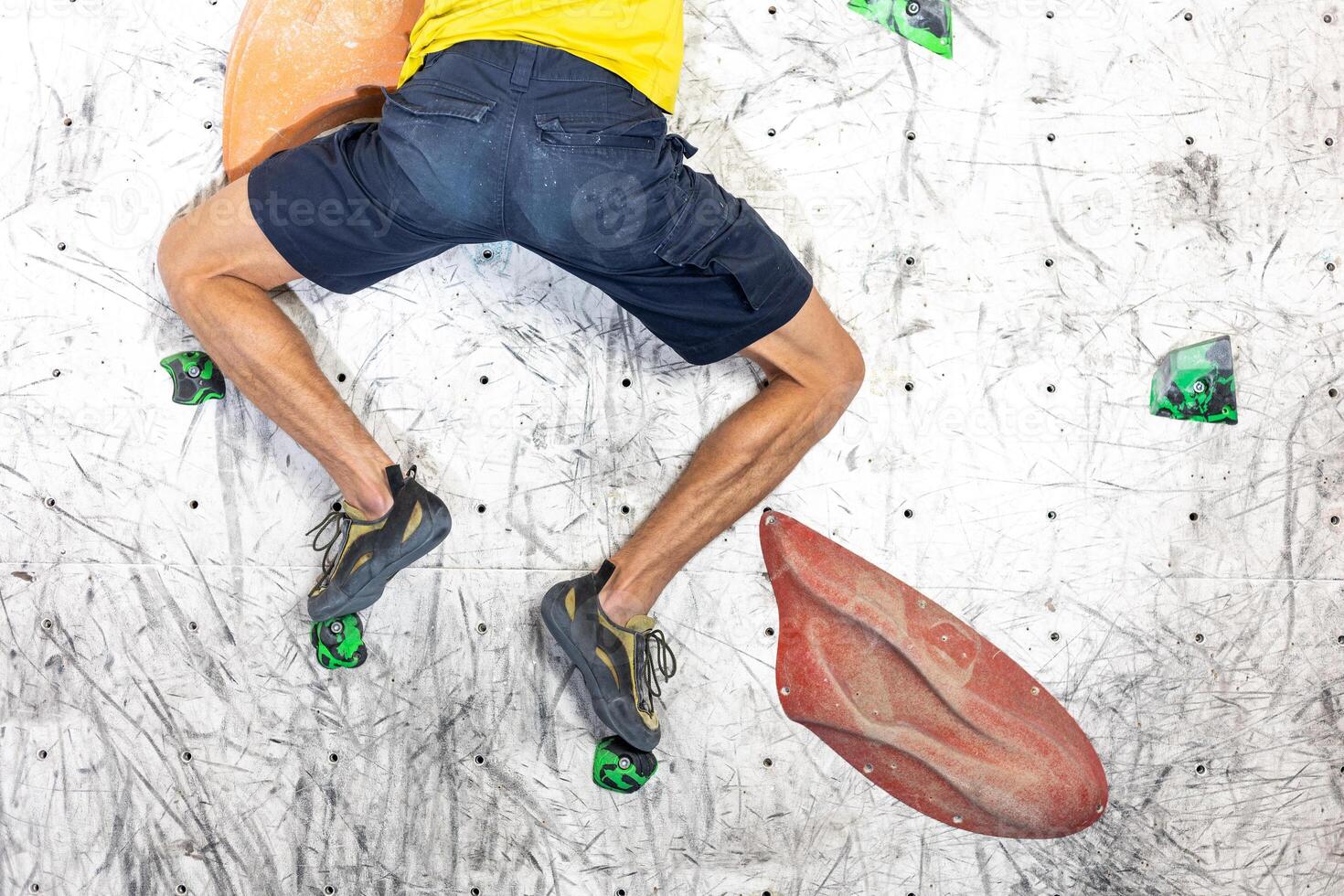 Close up view of young man or climber feet in climbing shoes on artificial indoor wall at climbing center, sport activity concept photo
