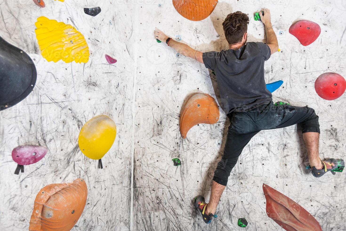 Young man climbing on the indoor climbing boulder wall with chalked hands photo