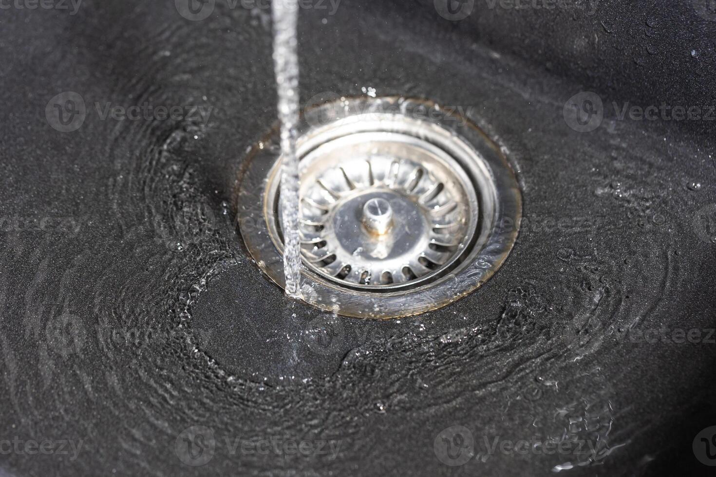 The water falling down from faucet to stainless sink and flow down to water hole, drink concept photo