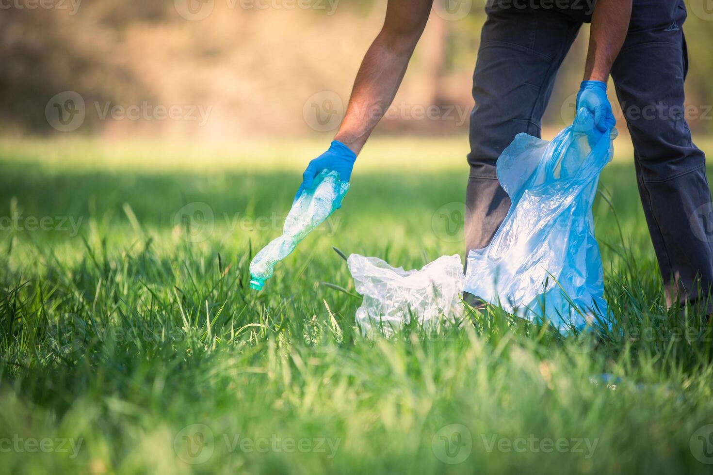 Man picking up plastic bottle, garbage collecting in forest cleaning planet, help garbage collection charity environment, garbage in the forest photo
