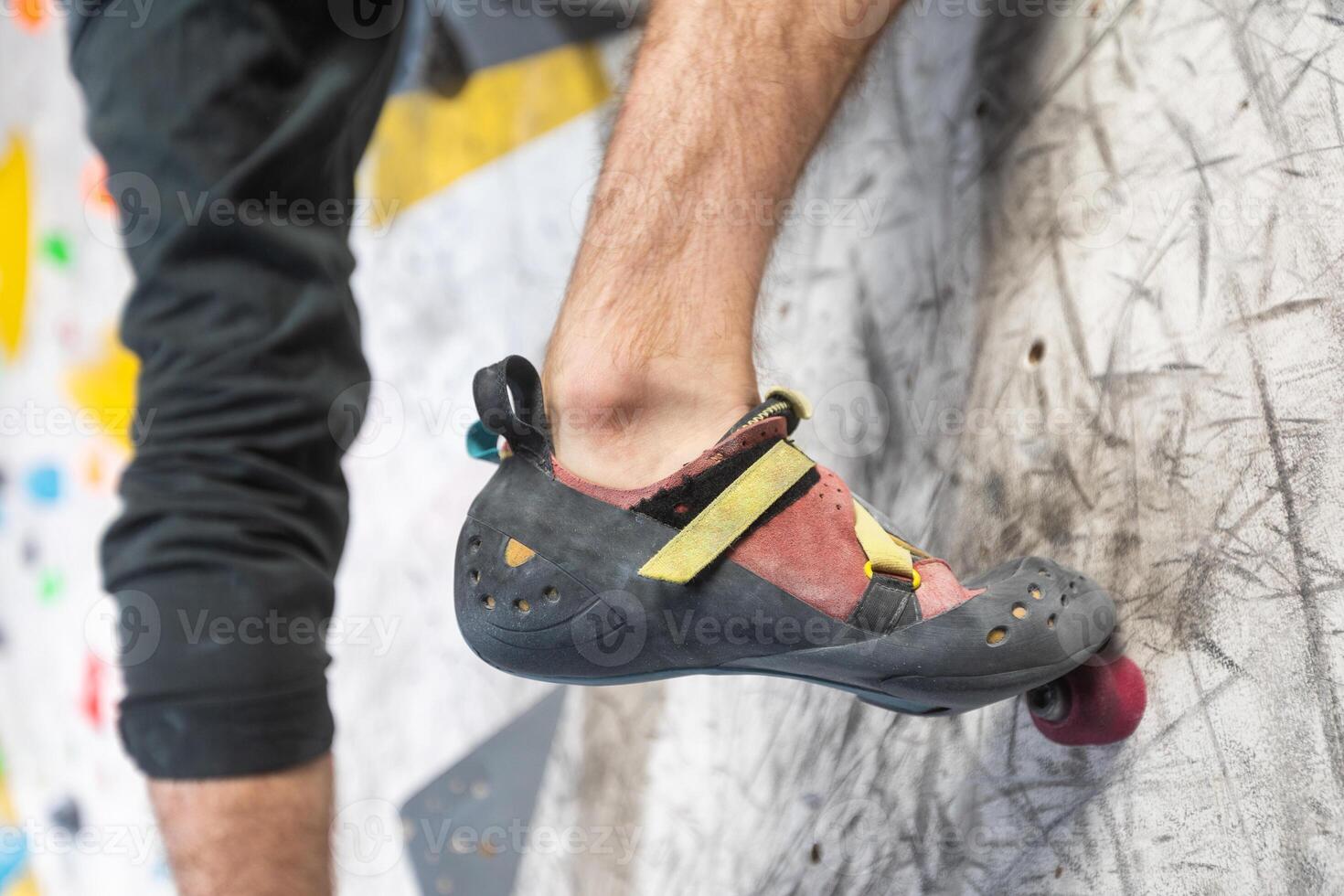 Close up view of young man or climber feet in climbing shoes on artificial indoor wall at climbing center, sport activity concept photo