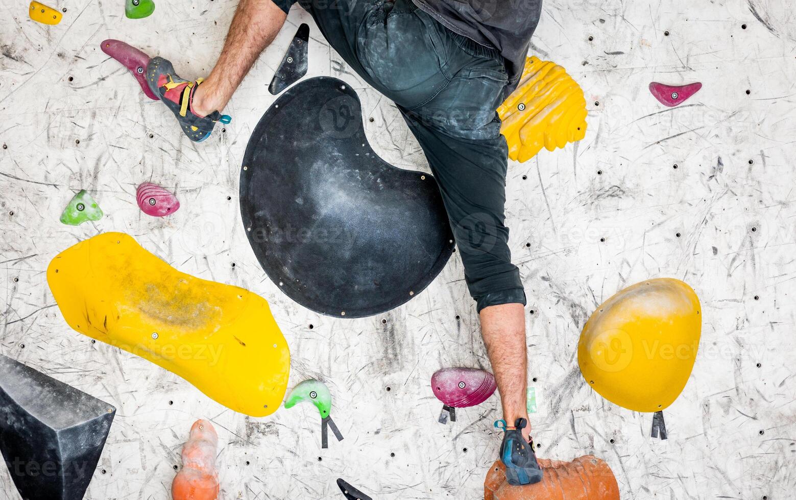 Close up of legs on the climbing grips, sportive man climbing the boulder wall in a climbing centre, sport activity concept photo