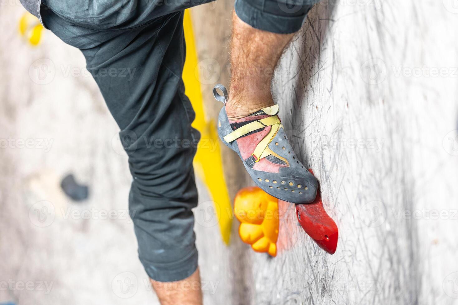 Close up view of young man or climber feet in climbing shoes on artificial indoor wall at climbing center, sport activity concept photo