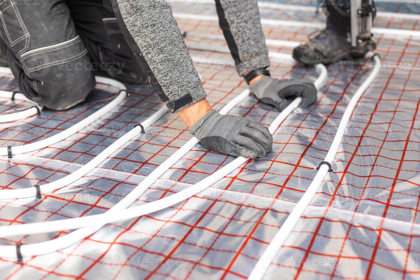 Worker installing underfloor heating system, water heating on the new residential house, concept of heated floor photo