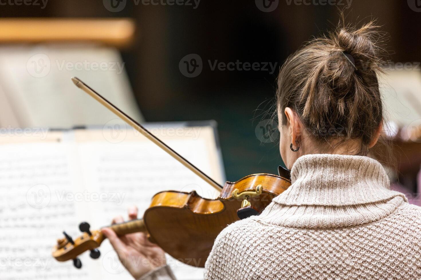 Professional symphonic string orchestra performing on stage and playing a classical music concert, violinist in a foreground photo