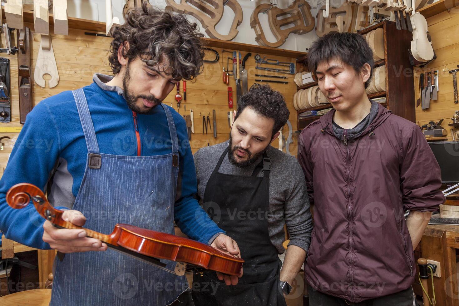 group of craftsmen violinmakers testing a new violin photo