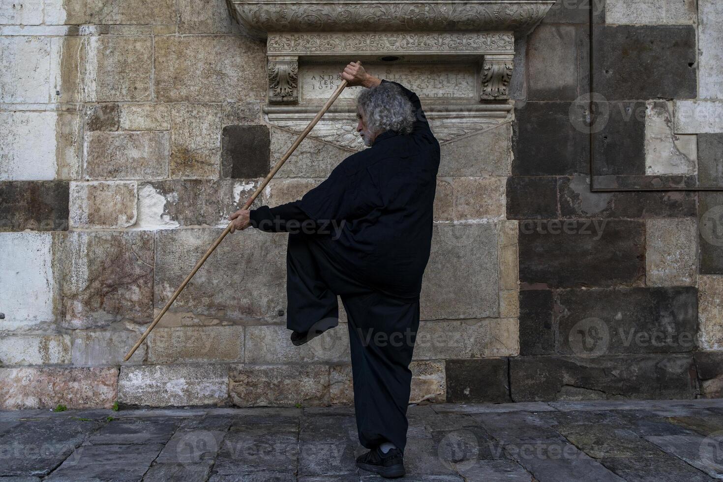 middle aged tai chi master showing stick exercises outdoors amidst the architecture of a medieval cathedral photo